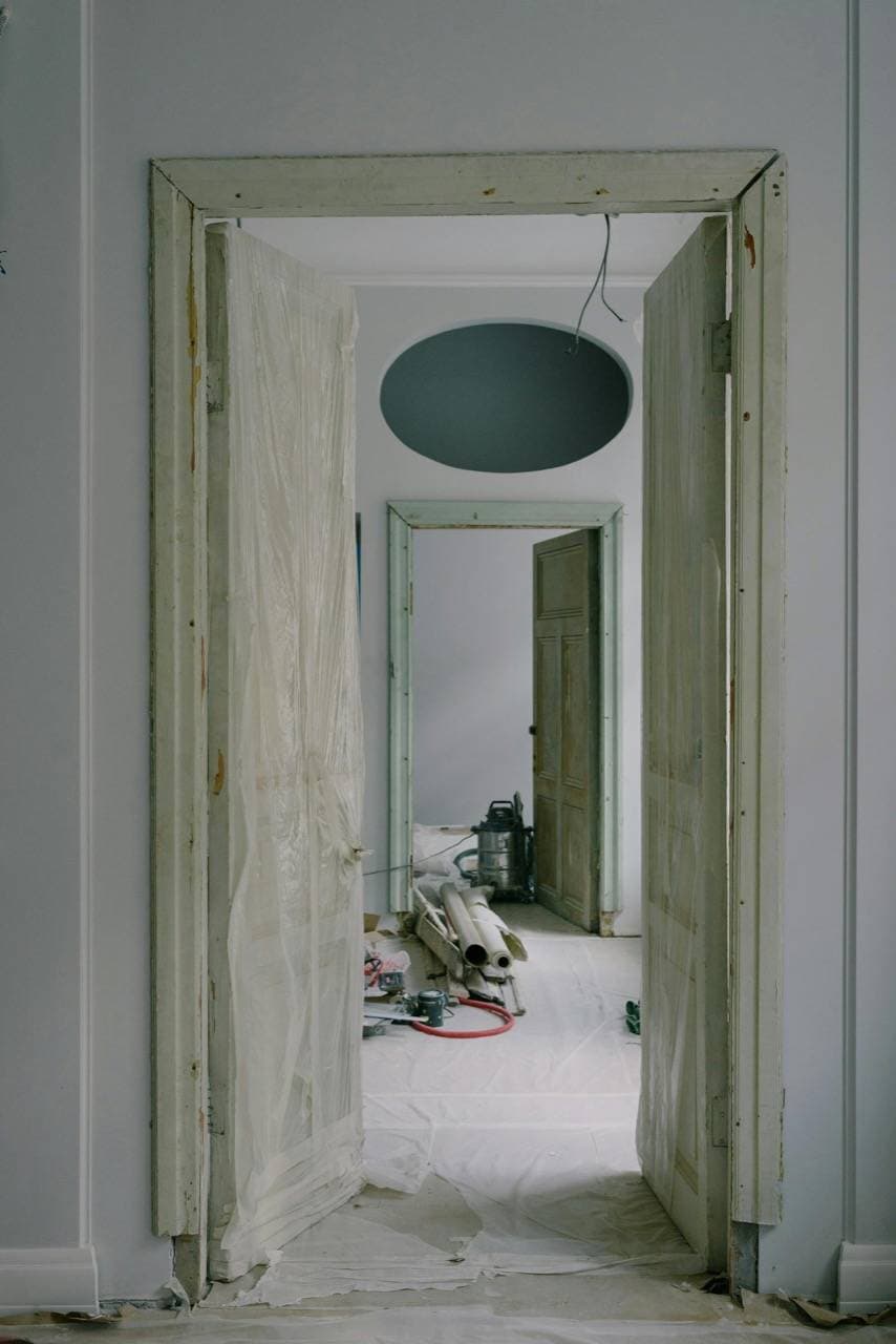Home interior mid-renovation, with a doorway opening onto a freshly painted room.