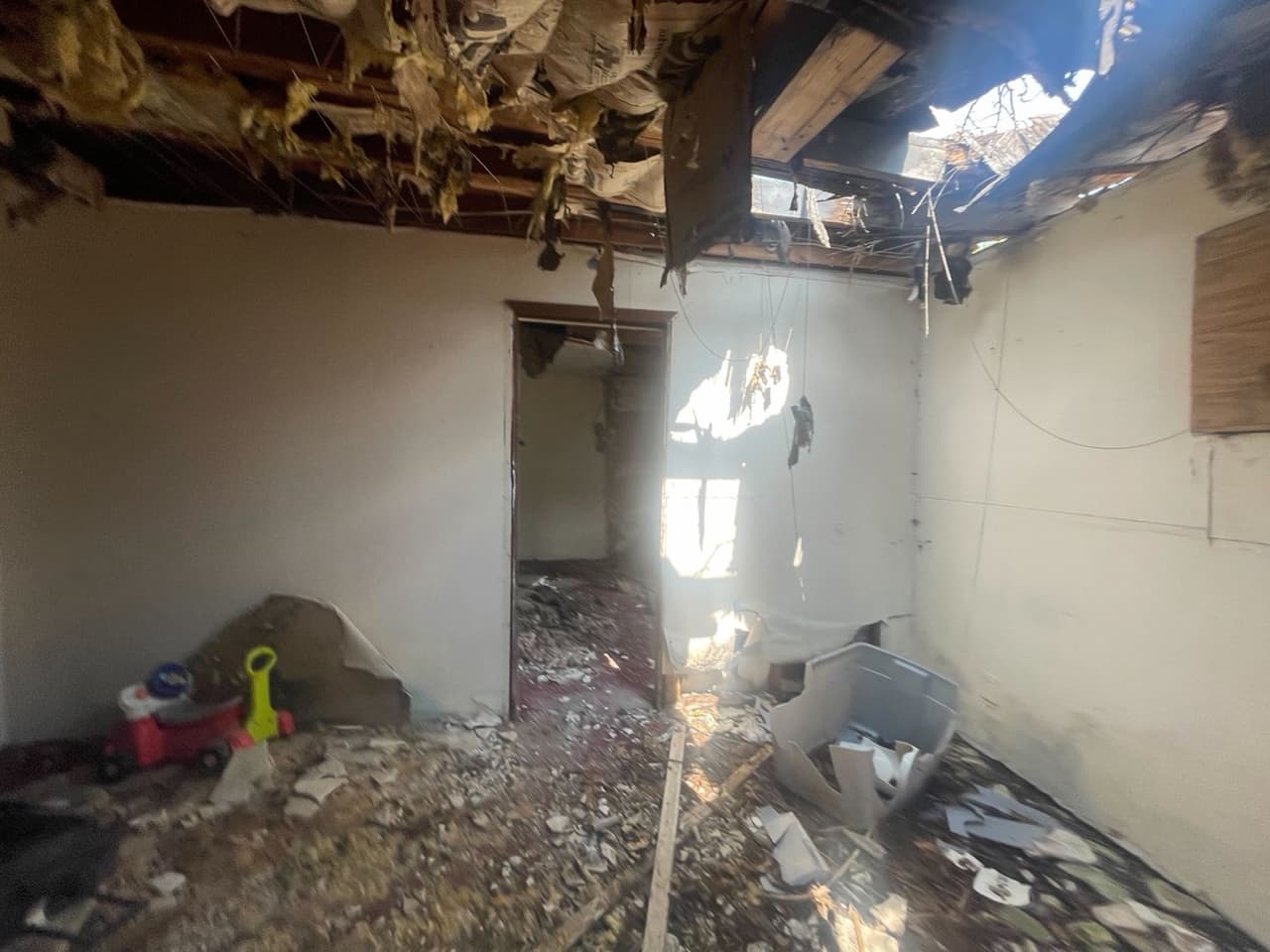 A second room before renovation with a caved-in roof and exposed framing